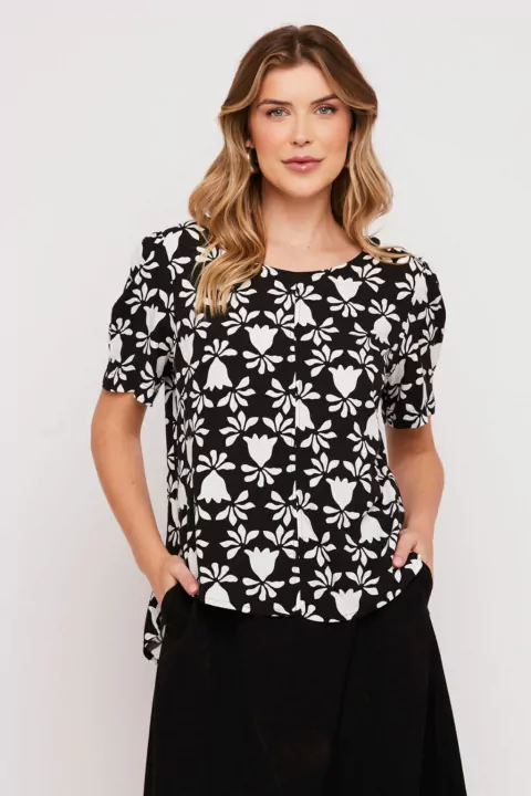 Modelo vestindo Blusa Canoa Viscose Preta Rubinella com estampa floral e mangas bufantes.