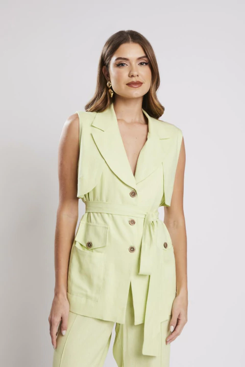 Mulher vestindo maxi colete verde claro de alfaiataria, sem mangas, com cinto e botões, ideal para looks elegantes e office look.