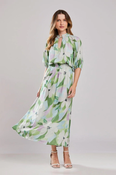 Mulher vestindo vestido midi floral Cascais com estampa em tons pastel, mangas 3/4 bufantes e tecido leve, ideal para o verão.
