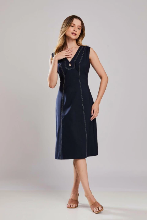 Mulher vestindo vestido tubinho alfaiataria Madison na cor marinho, sem mangas, com recortes e costuras aparentes, ideal para o verão.