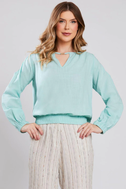 Mulher vestindo blusa bata de cotton slub na cor verde água, com mangas longas e detalhe no decote, ideal para o verão.