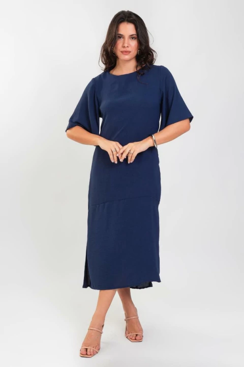 Mulher vestindo um vestido midi marinho com mangas amplas.