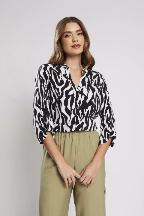 Mulher vestindo blusa estampada com padrão de zebra preta e branca, de manga longa, da categoria blusas femininas em promoção.