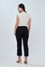 Mulher usando calça cropped reta preta, vista de costas, combinada com blusa clara e sandálias de salto.