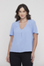Modelo usando a Blusa Decote V Azul Céu Rubinella, destacando o decote e as pregas frontais.