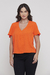 Modelo vestindo a Blusa Básica Decote V Laranja Rubinella, destacando o decote V e as pregas frontais.