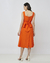 Mulher vestindo um vestido midi laranja com decote quadrado, visto de costas, com detalhe de laço na cintura.
