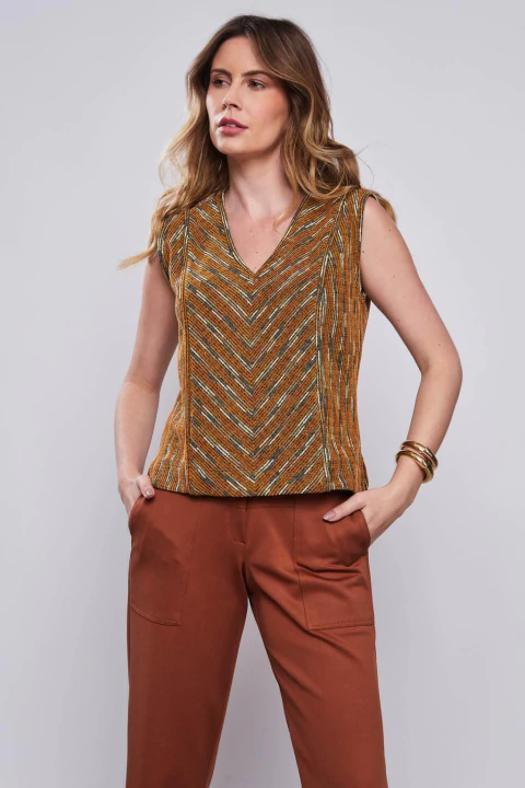 Mulher usando Blusa Tweed Solari Unica em tons de marrom e laranja, sem mangas, com padrão chevron.