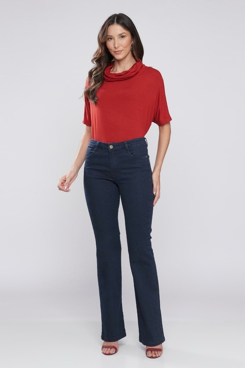 Mulher vestindo calça jeans boot cut básica de lavagem escura, combinada com blusa vermelha.