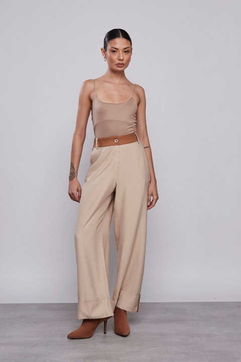Modelo vestindo a Calça Alfaiataria Helena Aveia, peça feminina de alfaiataria em tom bege, com cintura alta, corte reto e barra dobrada, ideal para looks de inverno e office look.