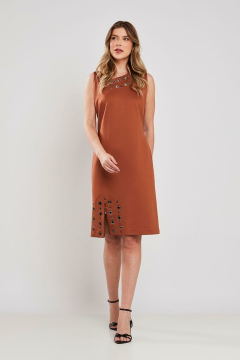 Modelo vestindo vestido midi marrom com ilhoses, sem mangas, ideal para o inverno e ocasiões elegantes.