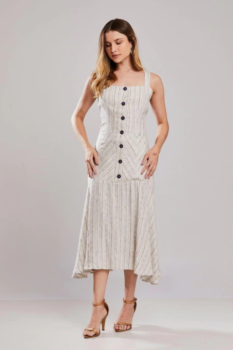 Mulher vestindo vestido alongado de alfaiataria Melua Unica, com alças largas, botões frontais e tecido claro com listras, ideal para verão e looks elegantes de trabalho.