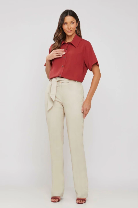 Mulher vestindo calça boot cut com amarração na cintura na cor areia.