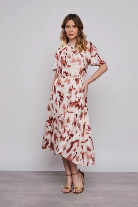 Mulher vestindo um vestido midi evasê com estampa de onça aquarelada, em fundo cinza.