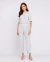 Mulher vestindo blusa gola canoa única e calça listrada em fundo branco.
