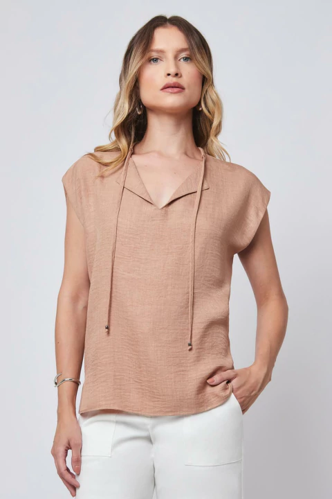 Mulher vestindo regata bege com amarração na frente.