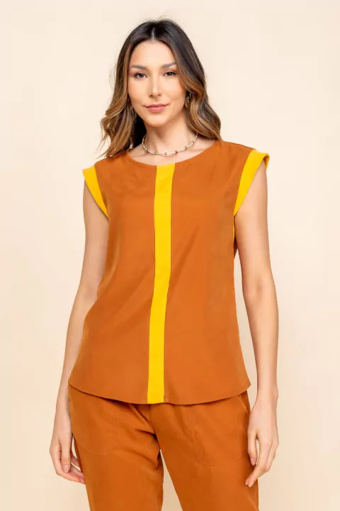 Modelo vestindo blusa bicolor Rubinella em ocre e amarelo, sem mangas e tecido aveludado.