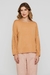 Modelo vestindo blusa Rubinella com mangas bufantes e decote redondo, na cor bege.
