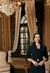 Mulher usando blazer preto de alfaiataria com detalhes em metal dourado em ambiente elegante.