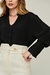 Modelo vestindo blusa feminina preta Versalhes, com calça branca e colar dourado.