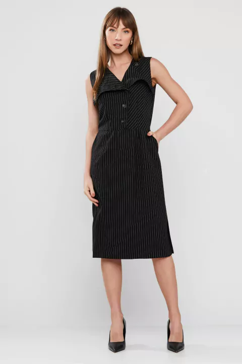 Mulher vestindo um vestido midi risca de giz preto, ideal para um look de escritório elegante.