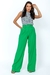Mulher vestindo calça pantalona alfaiataria verde e blusa estampada.