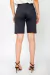 Bermuda Sarja Basic preta vista de costas, usada por modelo com blusa branca e salto alto.