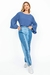 Mulher vestindo calça jeans mix em dois tons e blusa azul com mangas largas.