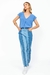 Mulher vestindo calça jeans mix com camiseta azul e tênis branco, em fundo branco.