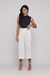 Mulher vestindo calça de sarja pantacourt off white e blusa azul escura.