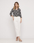 Look completo com Camisa Fleur Noir Preto Rubinella combinada com calça branca e sandálias douradas.