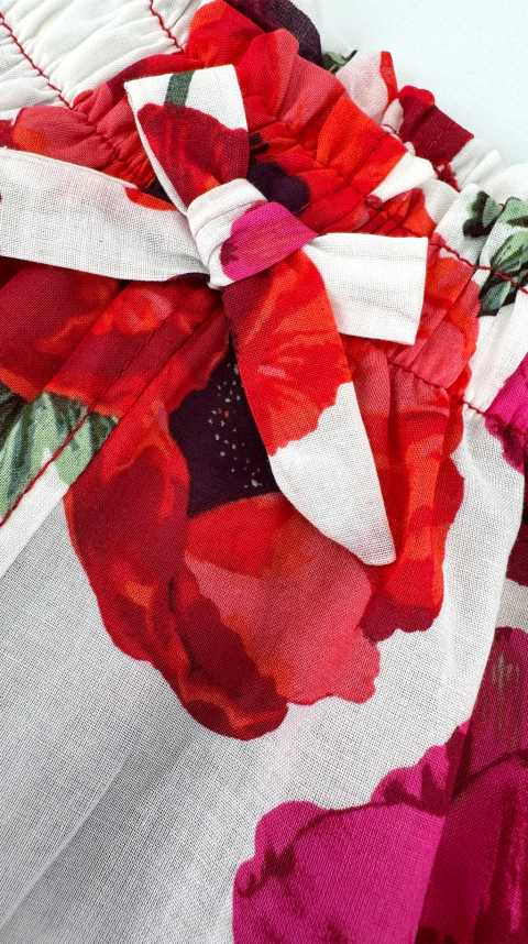 Detalle del short para bebés con estampado de amapolas rojas y fucsias y lazo decorativo en la cintura