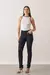 modelo vestindo calça jeans skinny preta com botões forrados, combinada com blusa branca sem mangas e sandálias de salto alto.