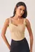 Cropped amêndoa feminino com alças largas, cor bege claro, sendo usado por modelo. Peça disponível na categoria outlet.
