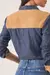 Camisa jeans feminina vista de costas, com detalhes em suede bege nos ombros e punhos.
