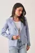Blazer feminino em linho azul claro com detalhe bordado na manga, usado sobre camiseta branca e calça jeans clara.