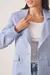 Blazer feminino em linho azul claro com detalhe bordado na manga, usado sobre blusa branca.