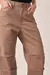 Close da cintura e dos detalhes das pinças da calça barrel em jeans avelã.
