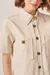 Detalhe da camisa off-white com bolsos e botão spike dourado