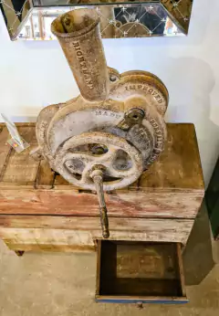 Debulhador de milho vintage sobre aparador de madeira de demolição, ideal para decoração diferenciada em ambientes internos.