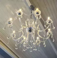 Lustre elegante de vidro com 8 braços e pingentes, destacando sua estrutura em ferro e cúpulas detalhadas da Marcenaria Tiradentes.