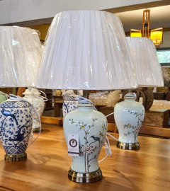 Abajur artesanal em cerâmica azul claro decorado com pássaros verdes e cúpula, ideal para iluminação e decoração sofisticada.