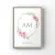 Quadro decorativo com monograma "AM" e flores de peônia em tons de rosa.
