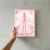 Quadro de Nossa Senhora Aparecida em rosa, com flores ao fundo e a imagem da santa em destaque.