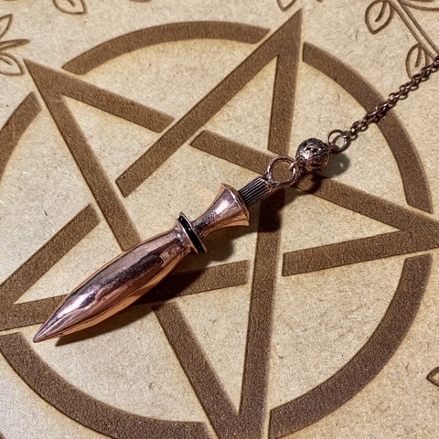 Pêndulo de cobre alongado e um pouco mais pesado, usado para fazer radiestesia e oráculos para bruxos e bruxas.