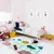Tapete de algodão colorido em um quarto infantil com cama, brinquedos e quadros na parede.