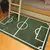 Tapete infantil em formato de campo de futebol, com linhas brancas em um fundo verde, colocado em um quarto.