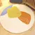 Tapete redondo infantil Kamet com design abstrato, apresentando formas geométricas em amarelo, laranja, azul e branco.