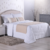 Conjunto de peseira e almofadas decorativas em cama queen, com colcha branca e detalhes em bege, em ambiente aconchegante.