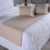 Peseira de cama queen na cor bege com almofadas brancas em cima de uma cama com lençóis brancos.